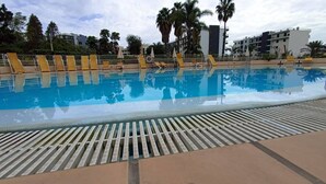 Ein Swimmingpool mit Liegestühlen und Palmen im Hintergrund.