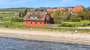 Un village côtier avec des maisons traditionnelles, une plage de sable et une mer calme.