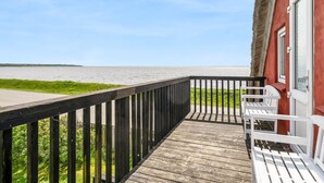 Une terrasse en bois avec des bancs blancs donnant sur une étendue d’eau.