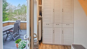 Ein Zimmer mit einer Schiebetür, die auf eine Außenpatio mit Tisch und Stühlen führt. Weiße, durchgehende Schränke mit Griffen sind ebenfalls zu sehen.