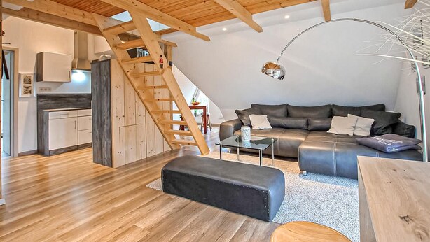 Ein geräumiger Loft mit Holzboden, einem Schlafsofa, einem Couchtisch und einer Küchenzeile.