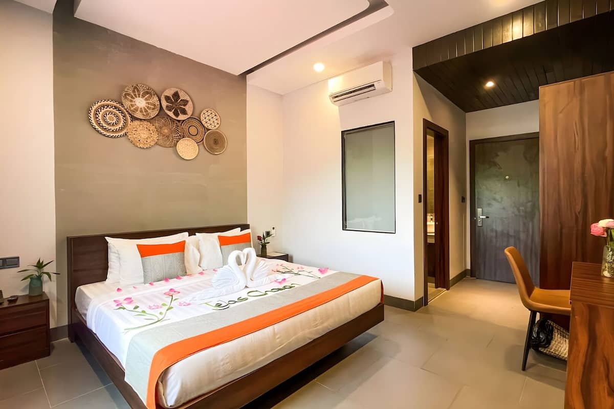 A modern hotel room with a large bed, a desk, and a wall decorated with woven art.