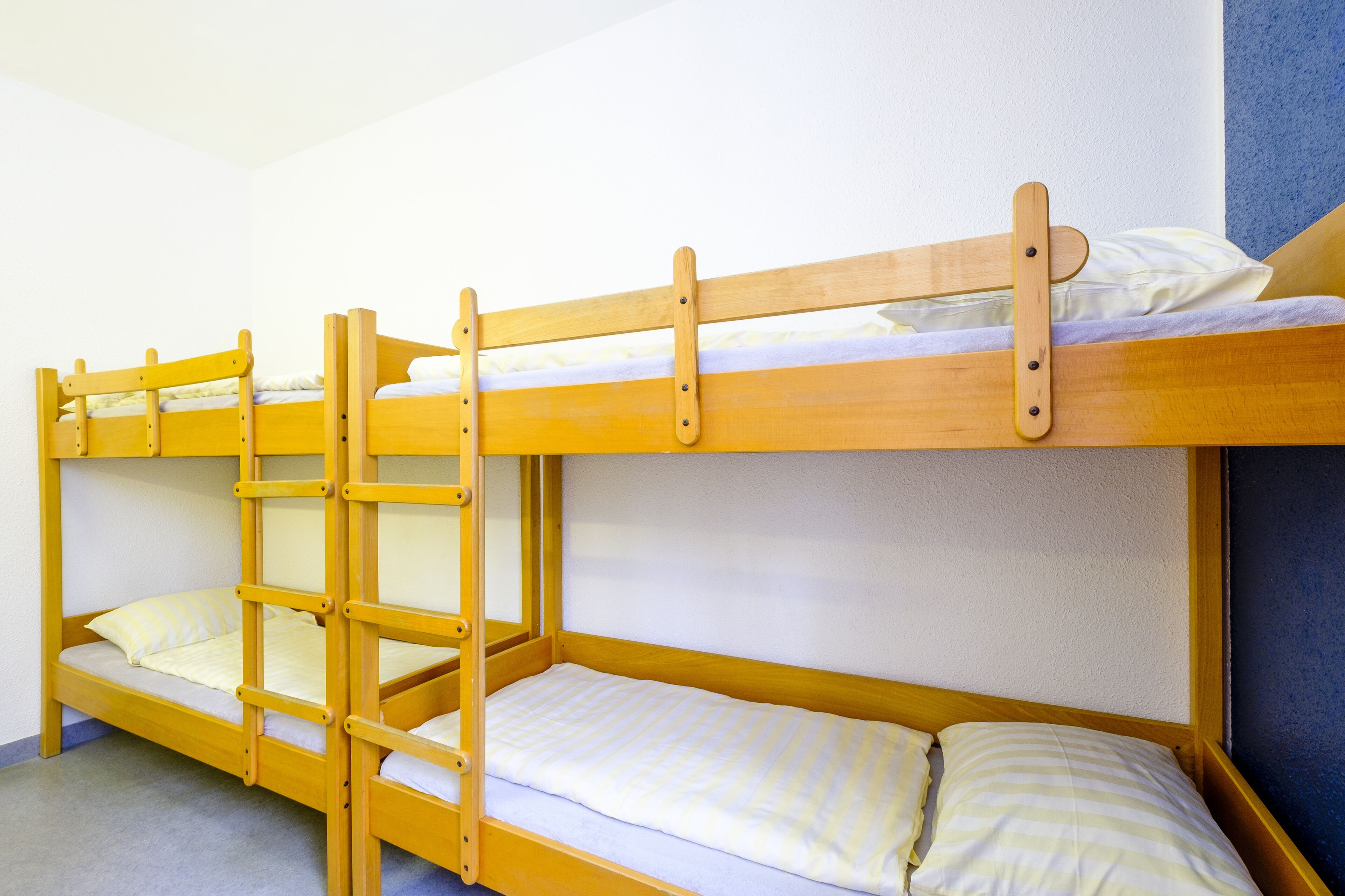 Uma cama beliche com dois níveis, cada um com travesseiro e cobertor.