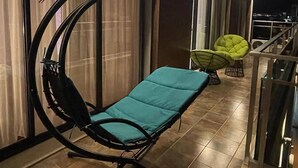 Moderni ulkotila, jossa on kaareva tuoli ja pehmustettu penkki, vihreä tuoli ja kaide.