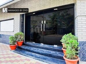 Een gevel met een glazen deur, plantenbakken en een bord waarop staat dat het pand beheerd wordt door OYO.