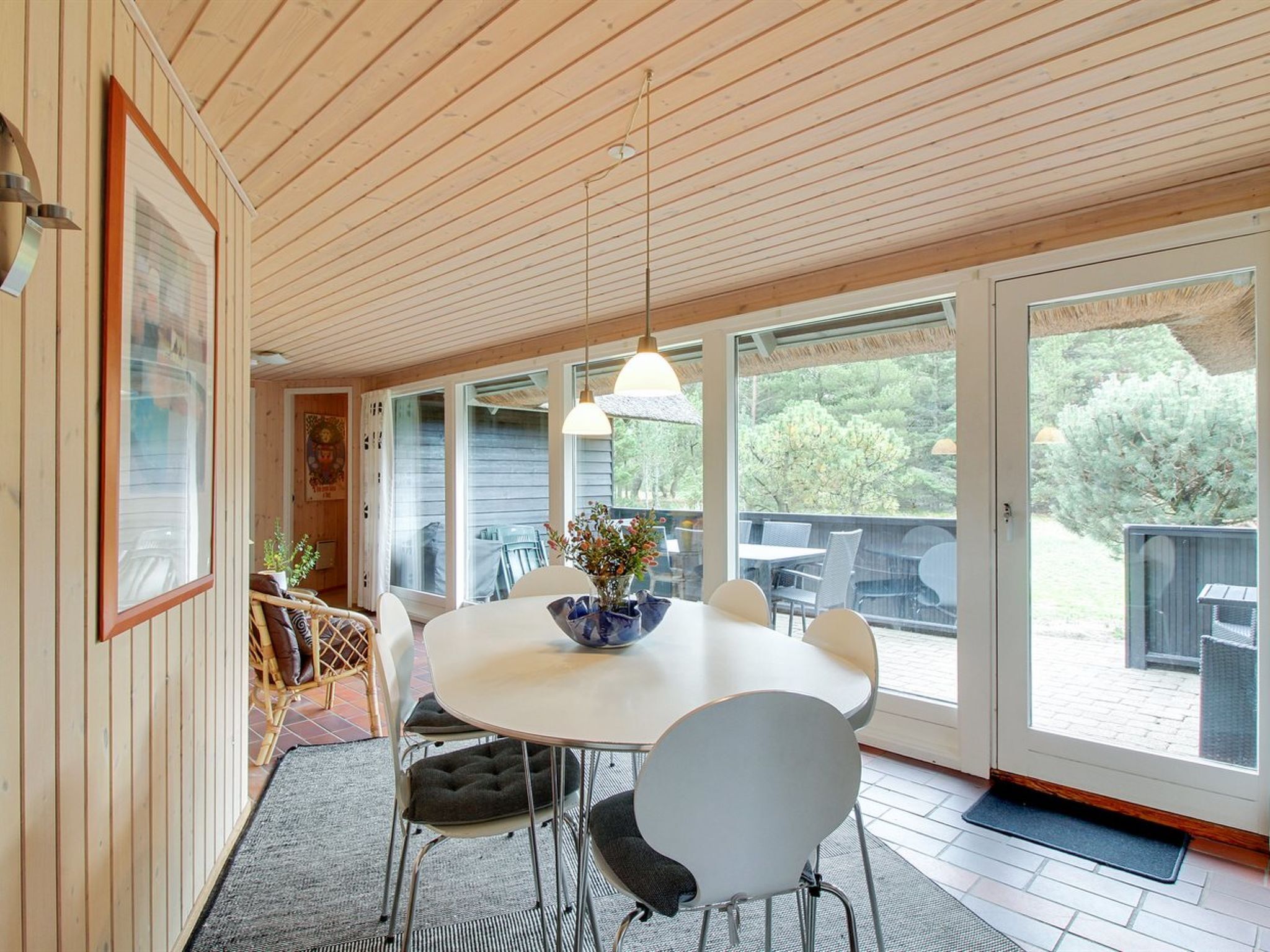 A dining area with a round table, white chairs, and a hanging light fixture.