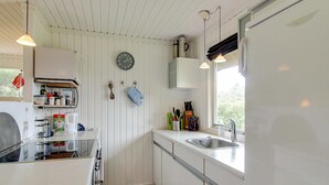 Cocina compacta con armarios blancos, un lavamanos, una estufa y un reloj en la pared.