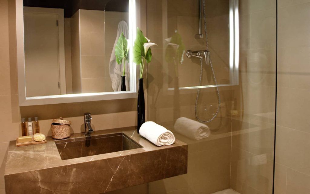 Une salle de bain moderne avec un lavabo en marbre, une douche en verre et un grand miroir.