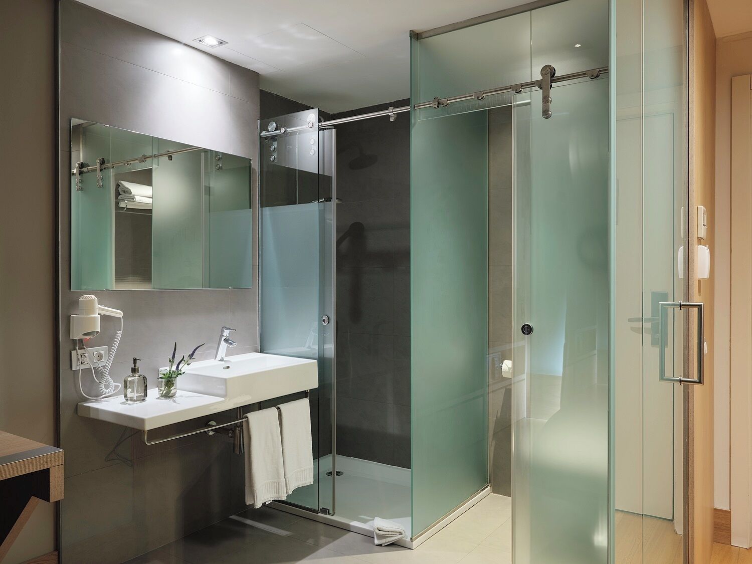 A modern bathroom with a glass shower enclosure, a vanity with a sink and mirror, and a towel rack.