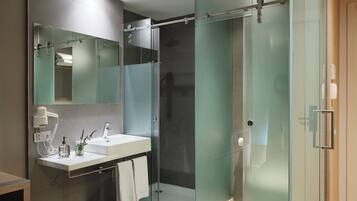 A modern bathroom with a glass shower enclosure, a vanity with a sink and mirror, and a towel rack.