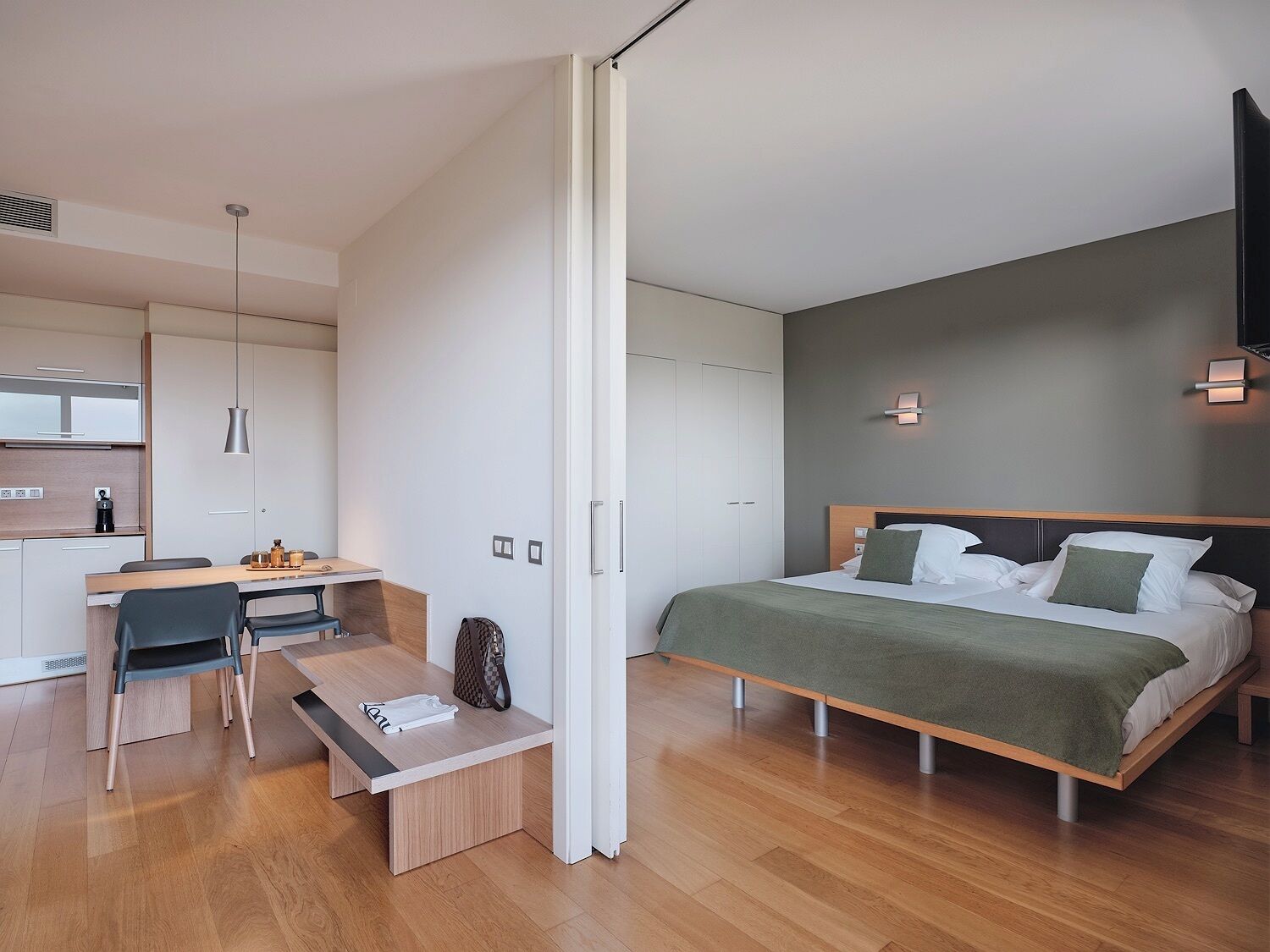 Una habitación de hotel moderna con cama, escritorio y kitchenette.