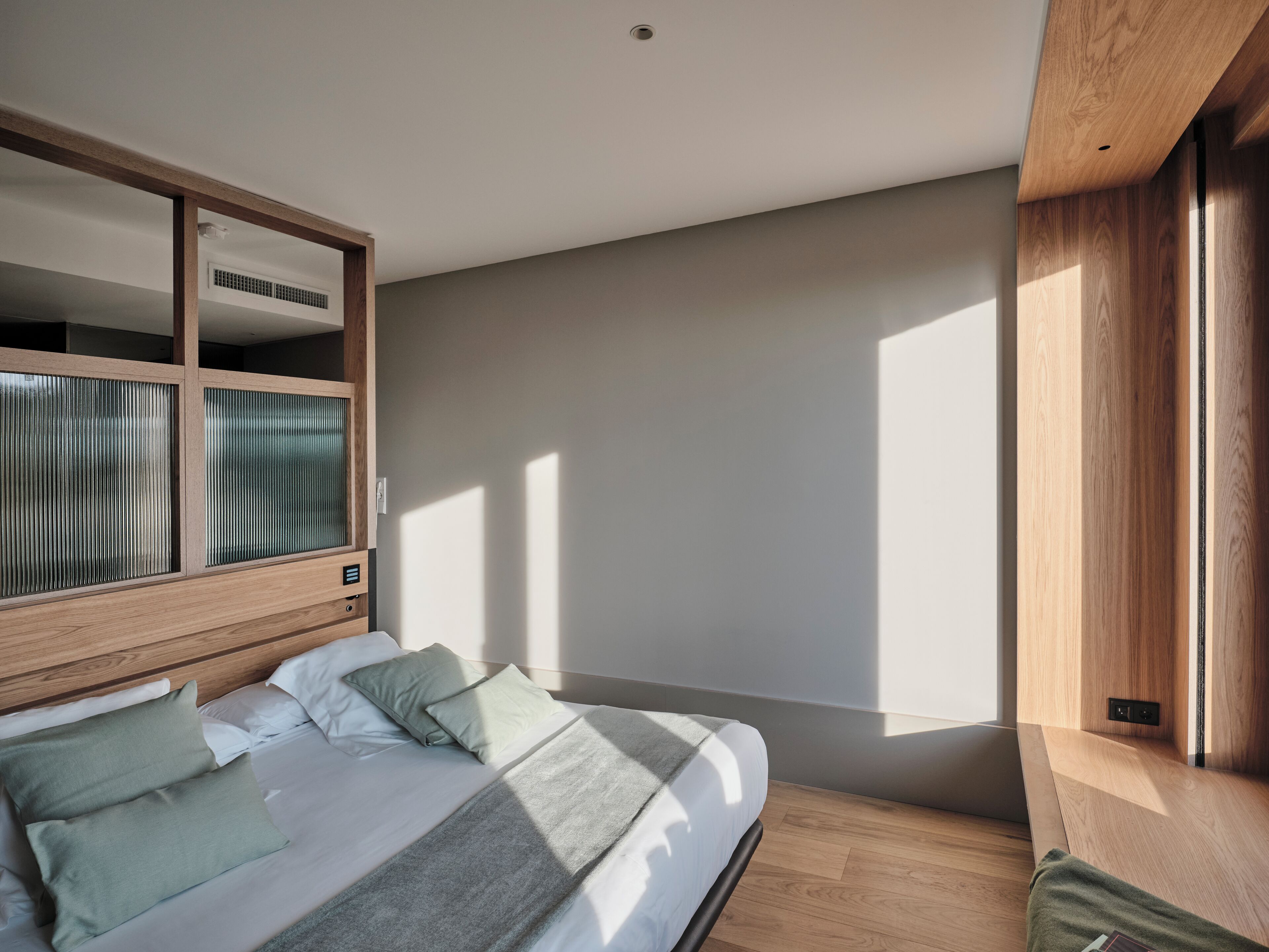 A modern bedroom with a bed, wooden headboard, and built-in storage.
