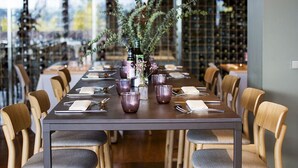 A long dining table set with purple glassware, a vase with flowers, and wooden chairs. - Qgat Suites & Events (Sant Cugat del Valles)