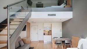 A modern apartment with a loft-style living area, a dining space, and a kitchenette. - Qgat Suites & Events (Sant Cugat del Valles)