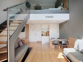 Un apartamento moderno con zona de estar tipo loft, comedor y kitchenette.