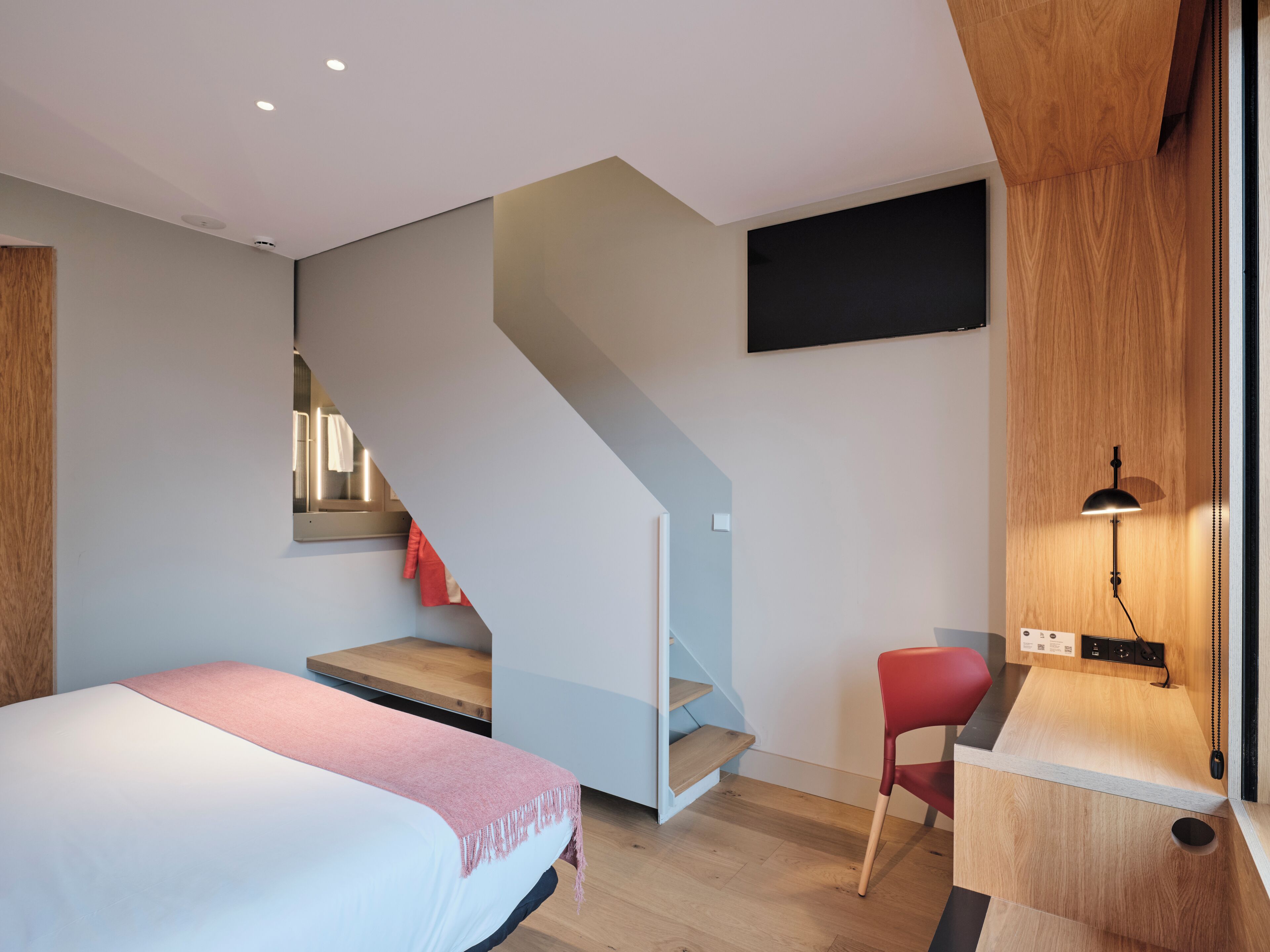 Ein modernes Schlafzimmer mit einem Bett, einem Schreibtisch und einer Treppe.