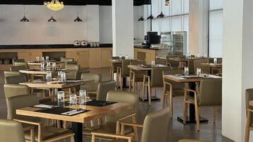 Un restaurante moderno con varias mesas, sillas e iluminación colgante.