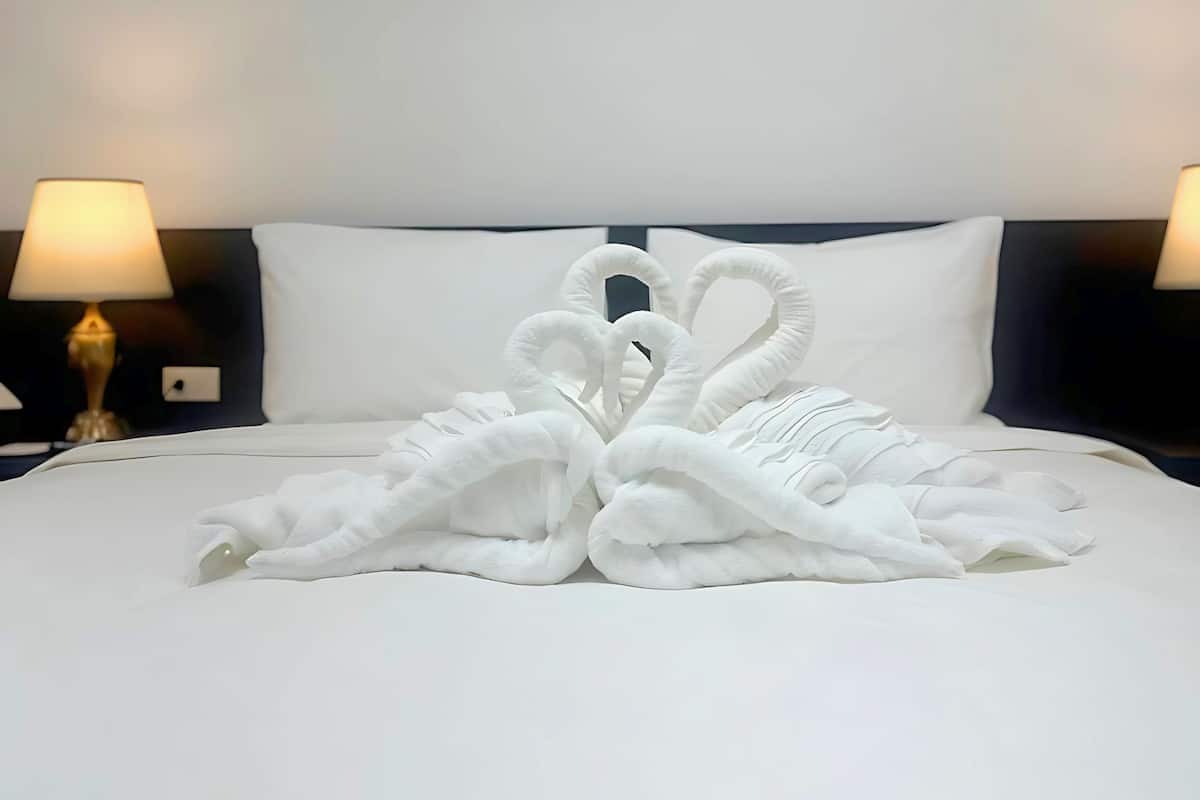 Un lit bien fait, avec une serviette pliée en forme de cygne.