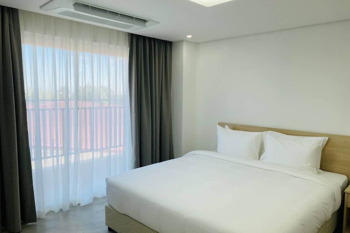 Une chambre d’hôtel avec un grand lit, une tête de lit en bois et une vue sur un balcon.