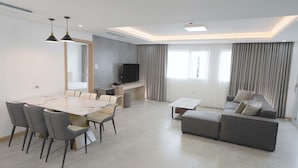 Una sala de estar moderna con una mesa de comedor, sofá y televisor.