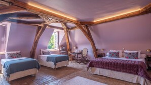 Une chambre avec deux lits, un plafond en bois et une grande fenêtre.