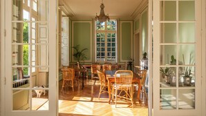 Un espace repas ouvert avec un plancher en bois, des chaises en osier et un lustre.