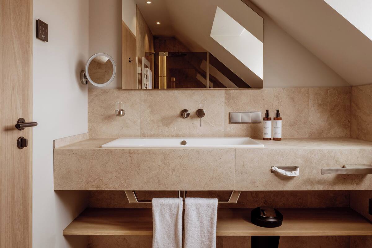 Un bagno moderno con un lavandino ampio, uno specchio e un porta asciugamani.