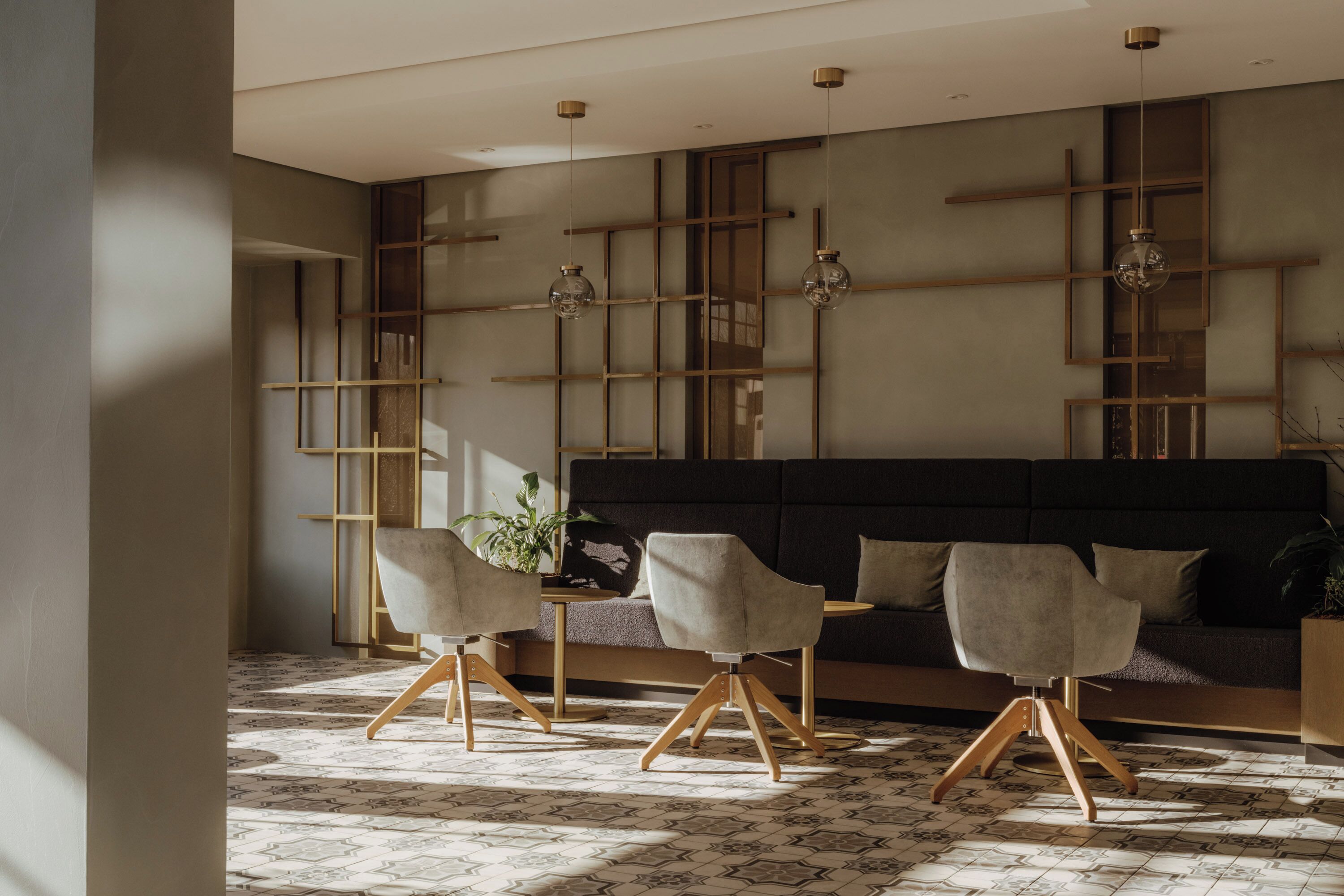 Ein stilvolles Wohnzimmer mit einer Couch, drei Sesseln, einem Couchtisch und Pendelleuchten.