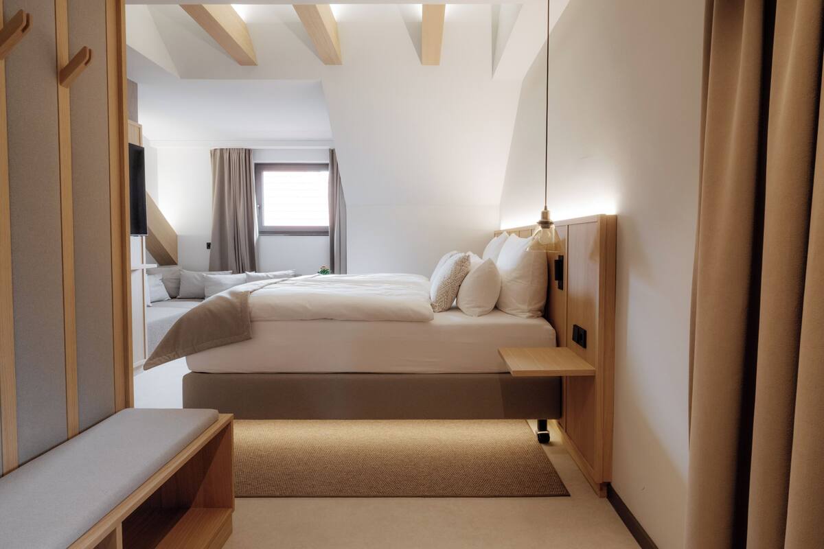Una moderna camera d'hotel con un letto grande, comodini, una panca e una TV.