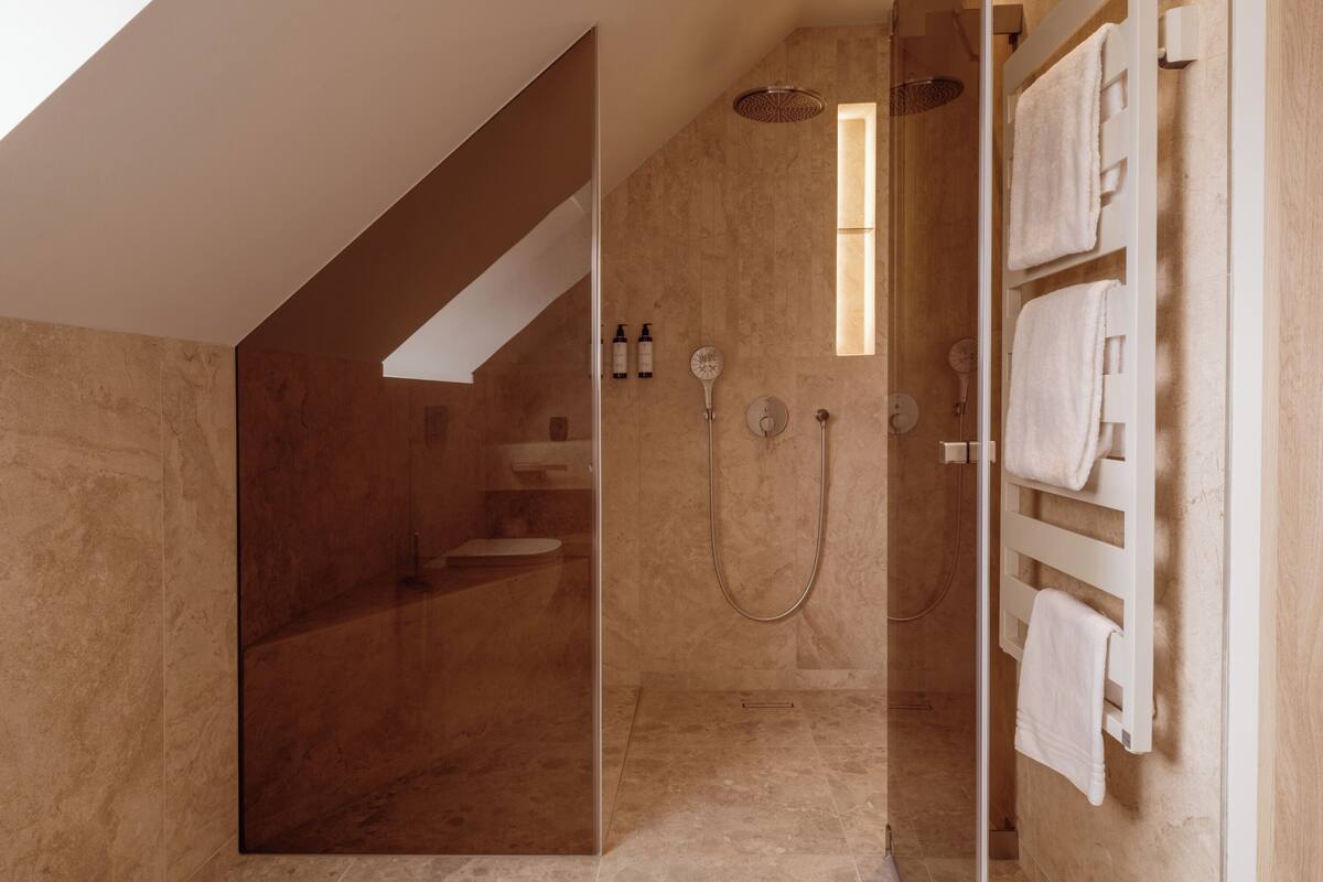 Un bagno moderno con cabina doccia in vetro, un water incassato e un porta asciugamani.