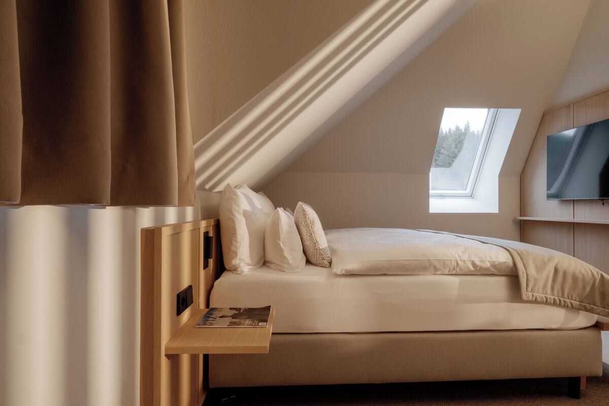 Una camera da letto con un letto, un comodino, una TV e un lucernario.