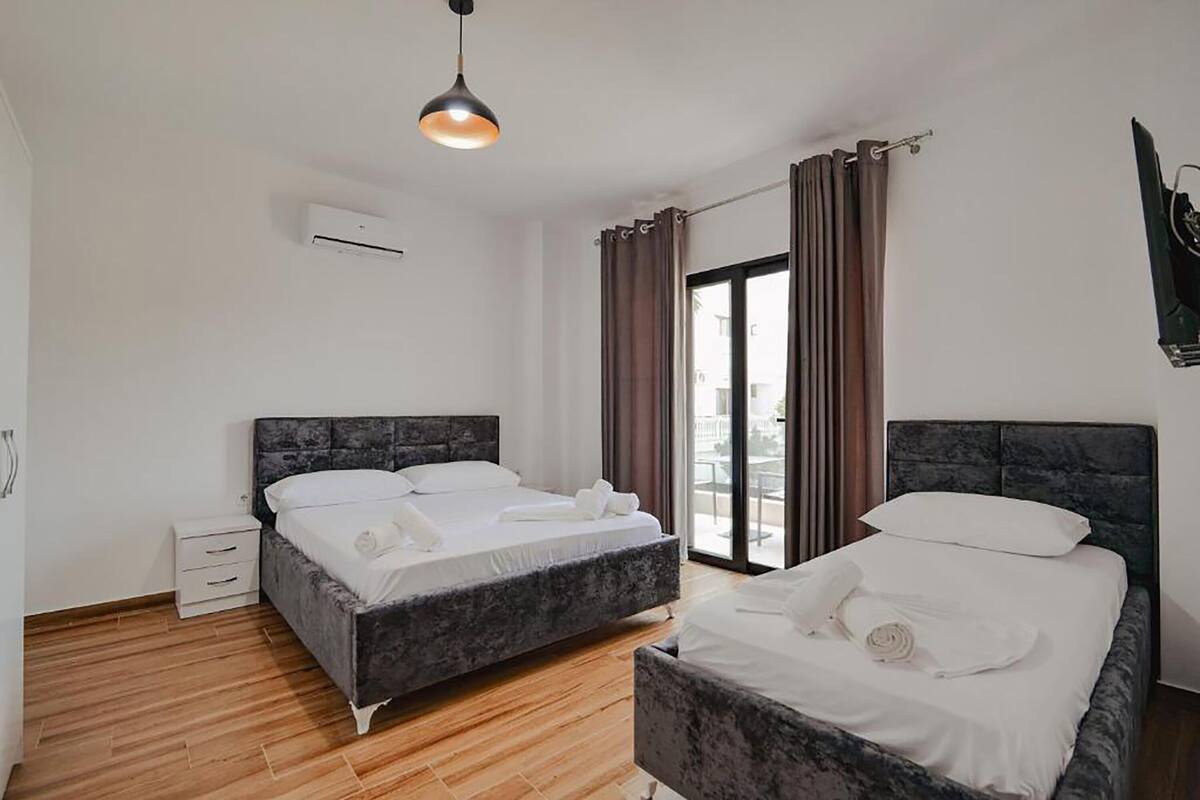 A modern hotel room with two beds, a large window, and a balcony.