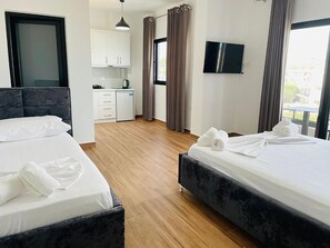 A hotel room with two beds, a kitchenette, a TV, and a view of the outdoors. - Vila Muka (Ksamil)