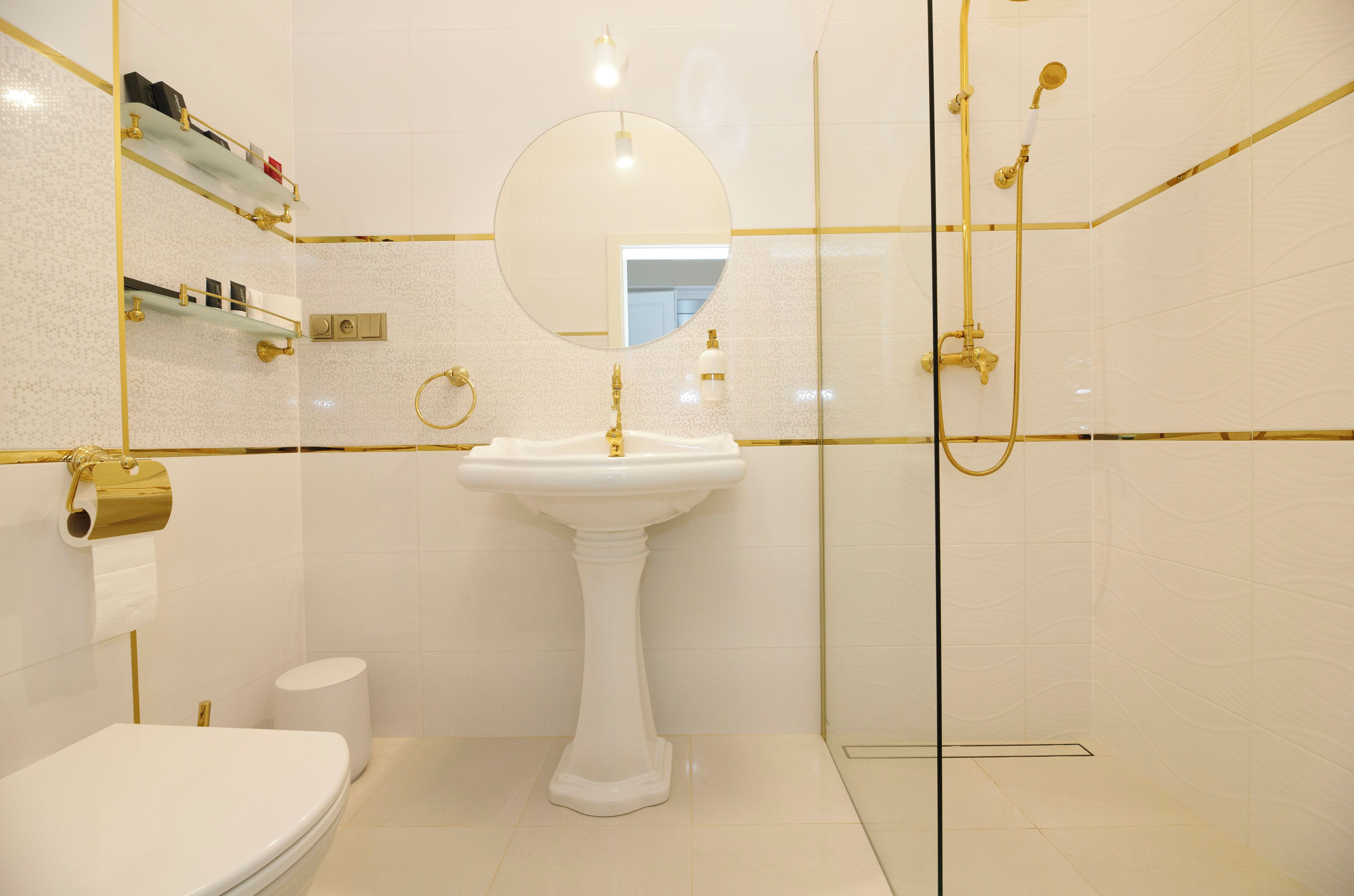 A bathroom with a pedestal sink, toilet, and glass-enclosed shower.