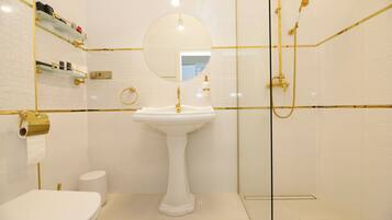 A bathroom with a pedestal sink, toilet, and glass-enclosed shower.