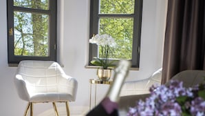 Een kamer met een glazen tafel, een witte stoel, een vaas met bloemen en een champagnefles in een emmer.