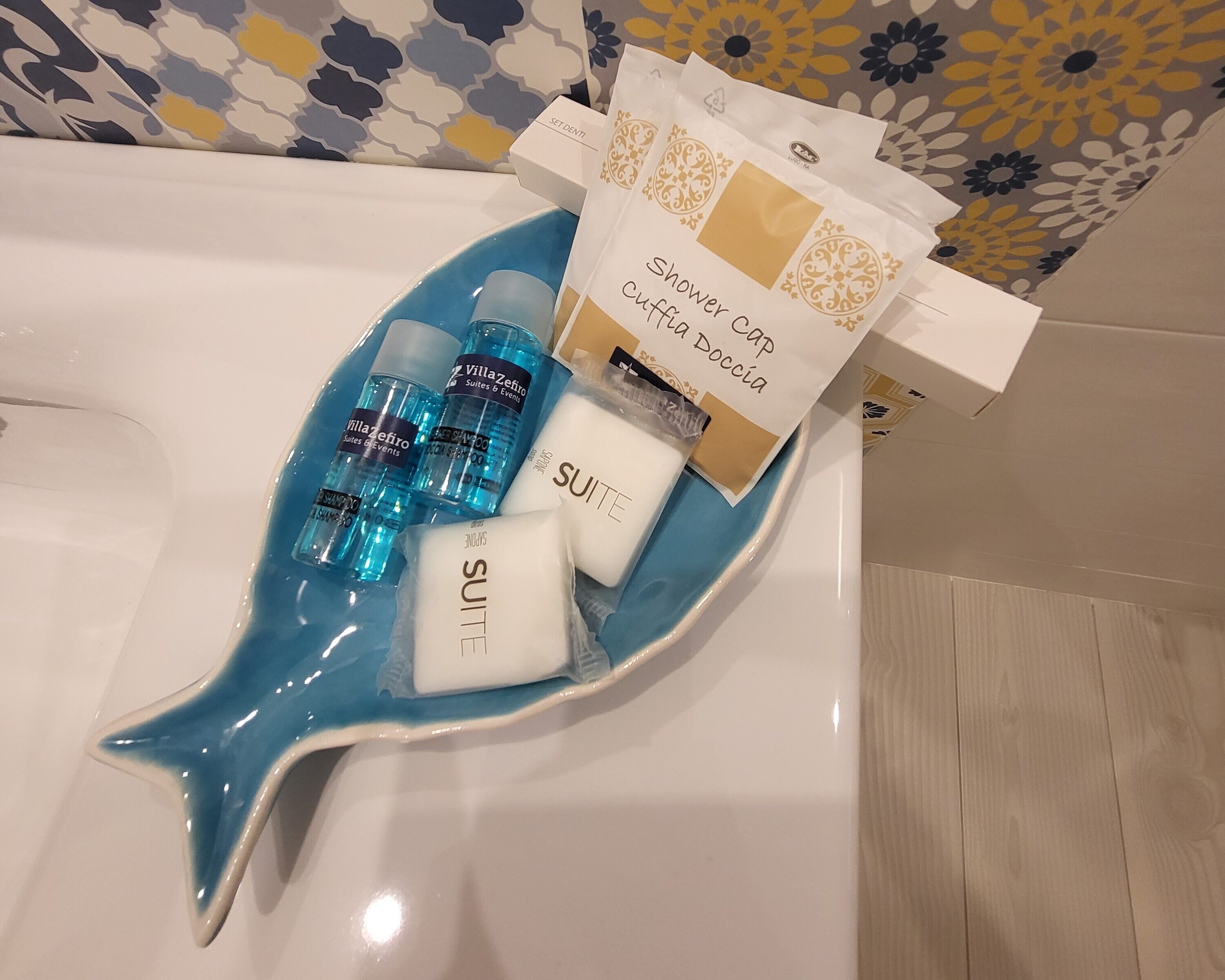 Un lavamanos de baño con artículos de aseo, incluyendo un jabonera azul en forma de estrella, una toalla blanca y botellas azules de champú y acondicionador.