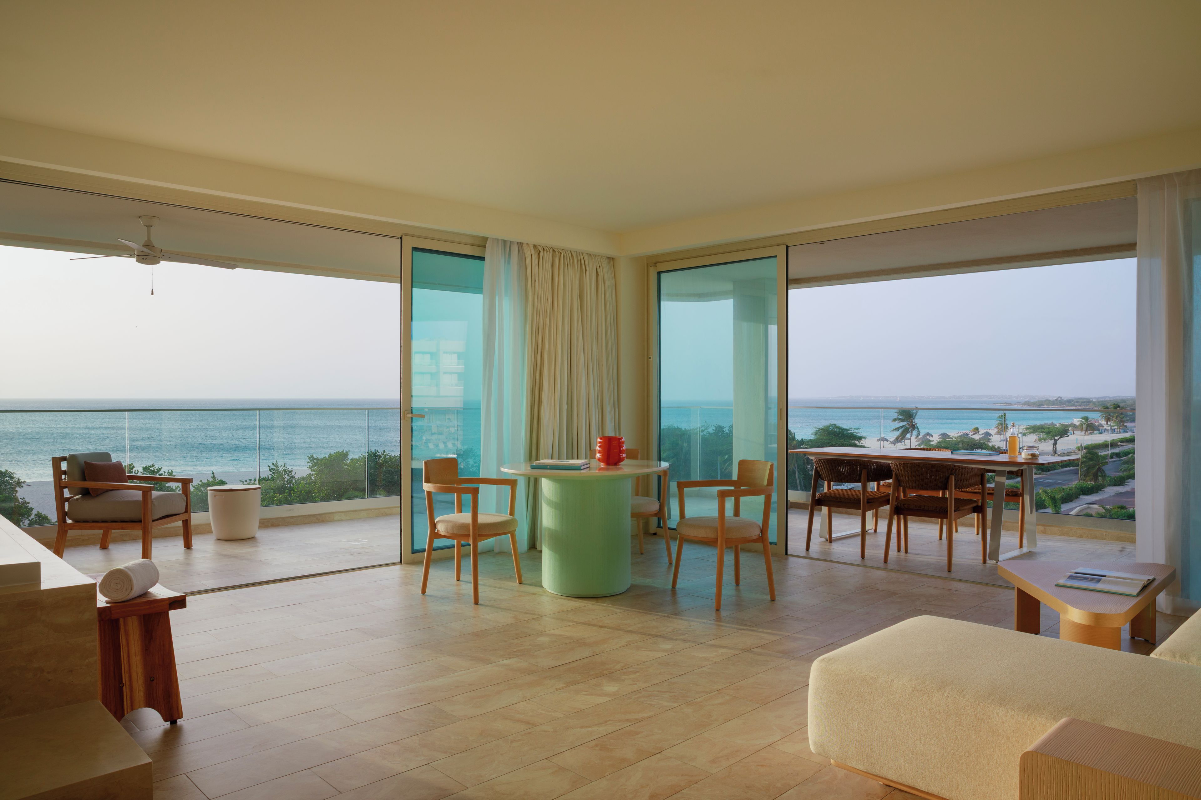 A spacious balcony with a view of the sea, furnished with chairs and a table.