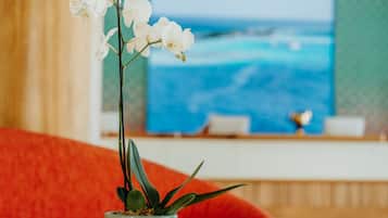 A wooden table with a potted orchid and a television in the background.