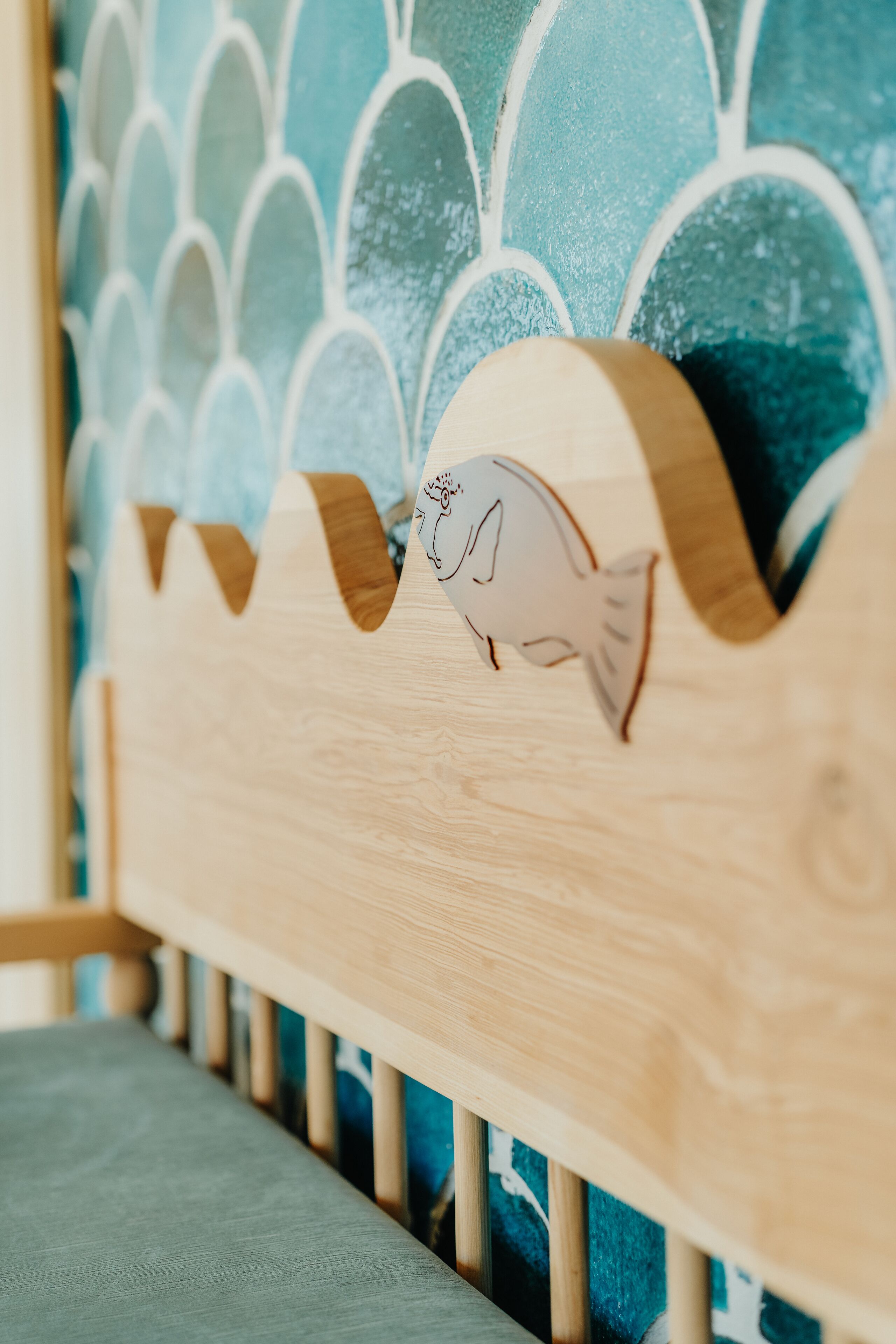 Una cuna de madera con diseño de olas en la cabecera.