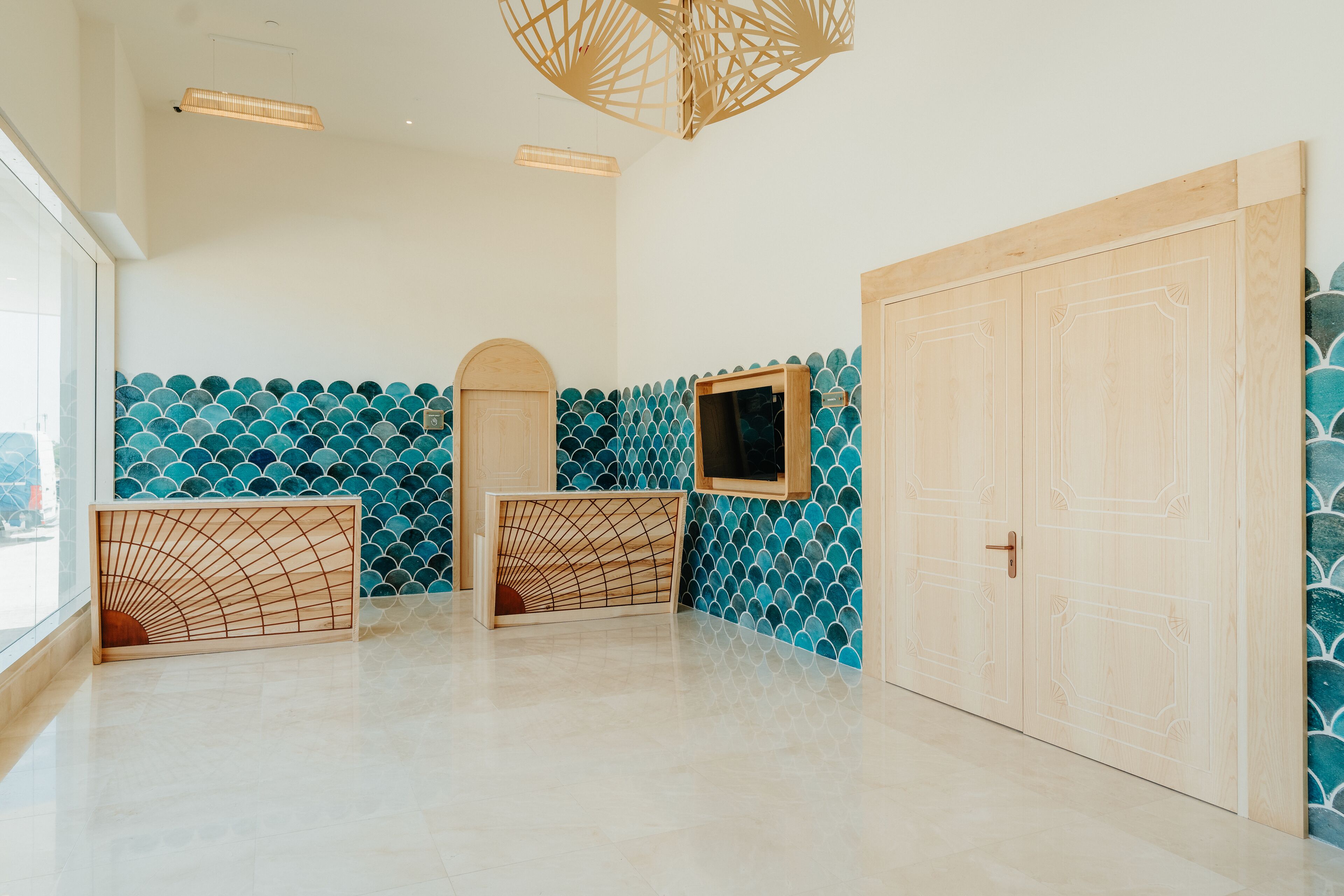 Una habitación con pared de baldosas, puerta de madera y una lámpara en el techo.