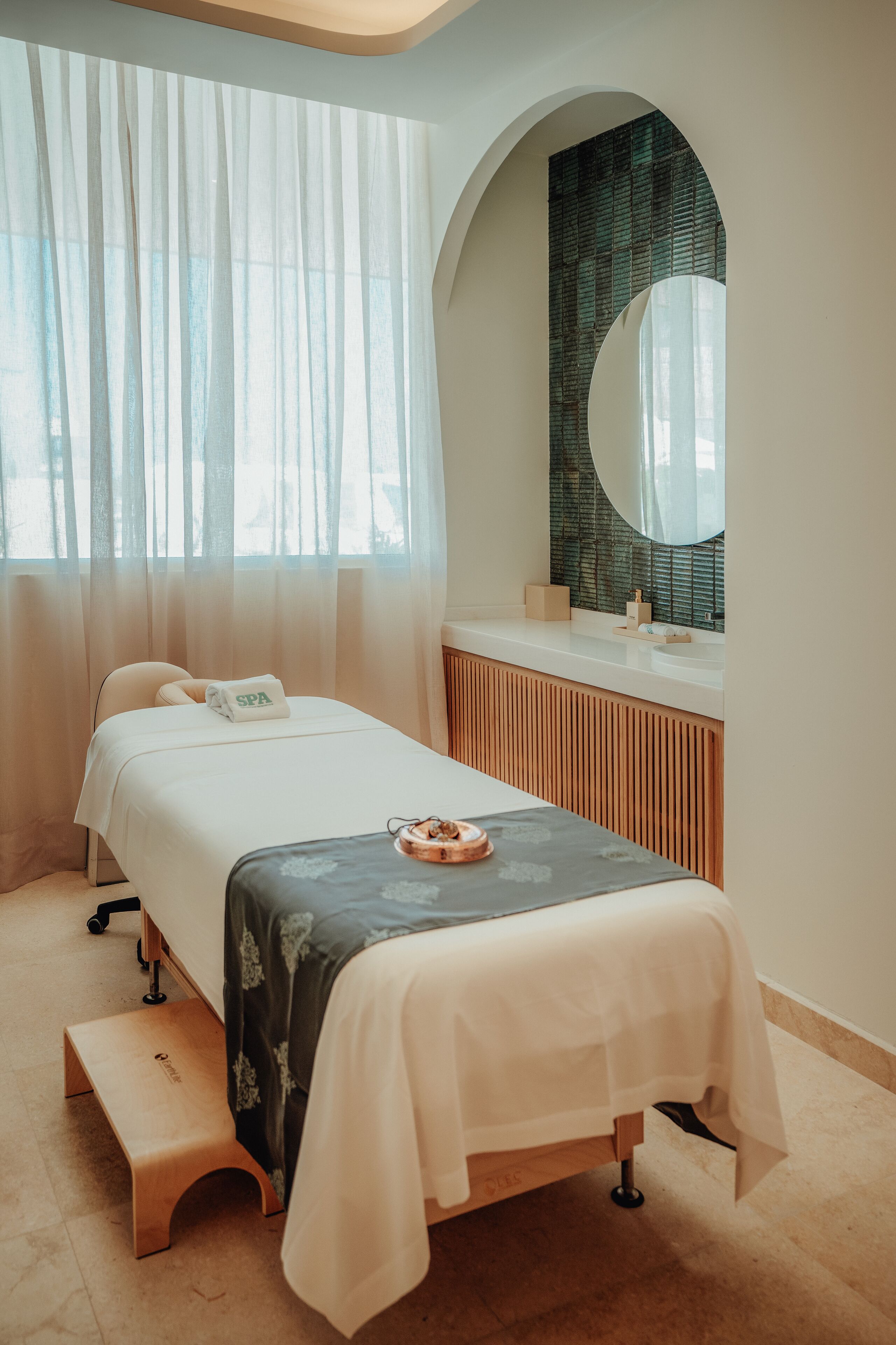 Een wellnessruimte met een bed, een bank en een grote spiegel.