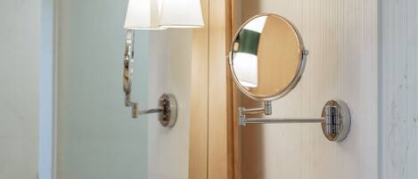 A bathroom with a large mirror, wall-mounted light fixtures, a sink, and two soap dispensers.