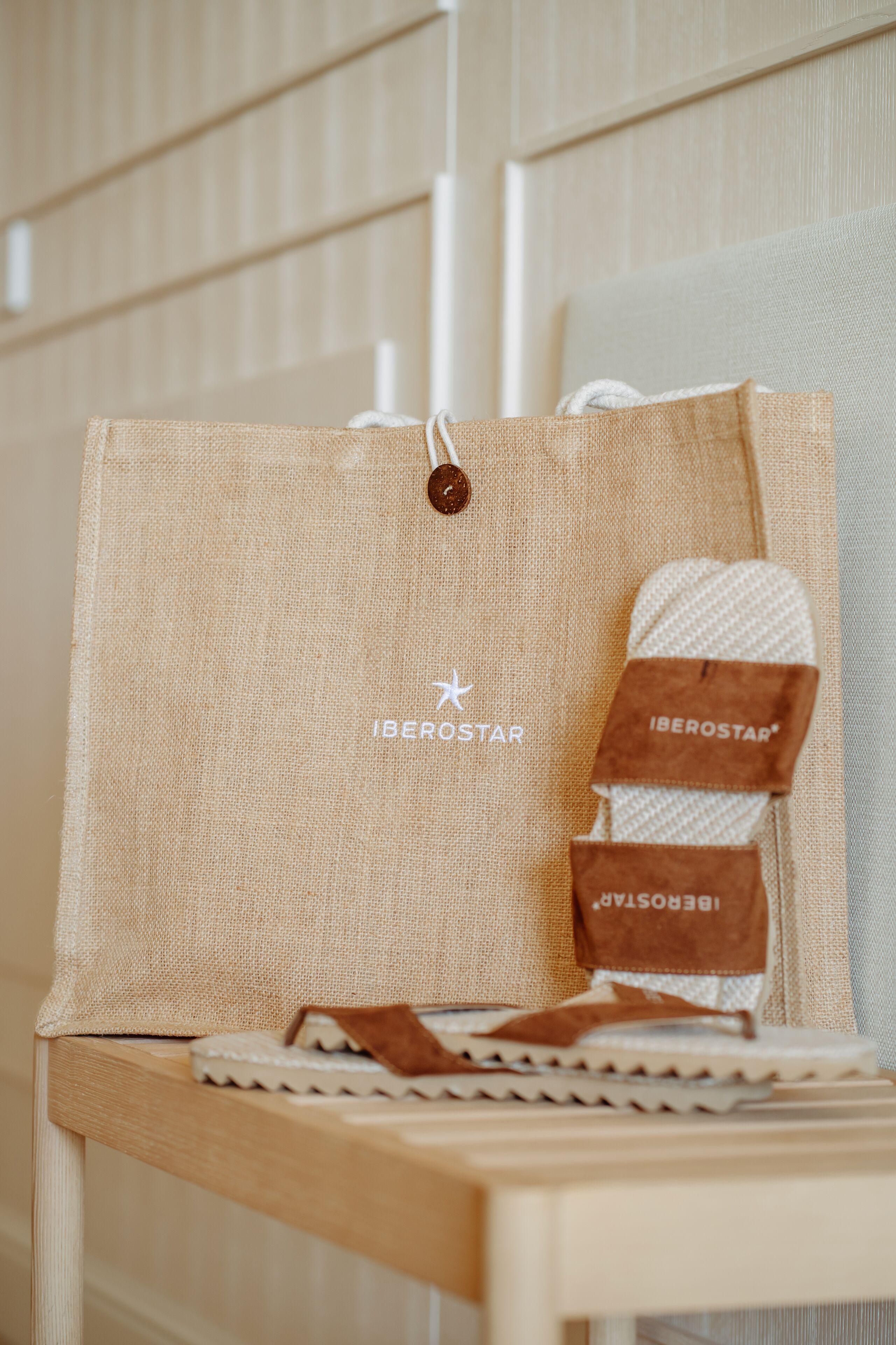 Una bossa de jute amb el nom de marca "IBEROSTAR" i un parell de corretges de cuir marró.