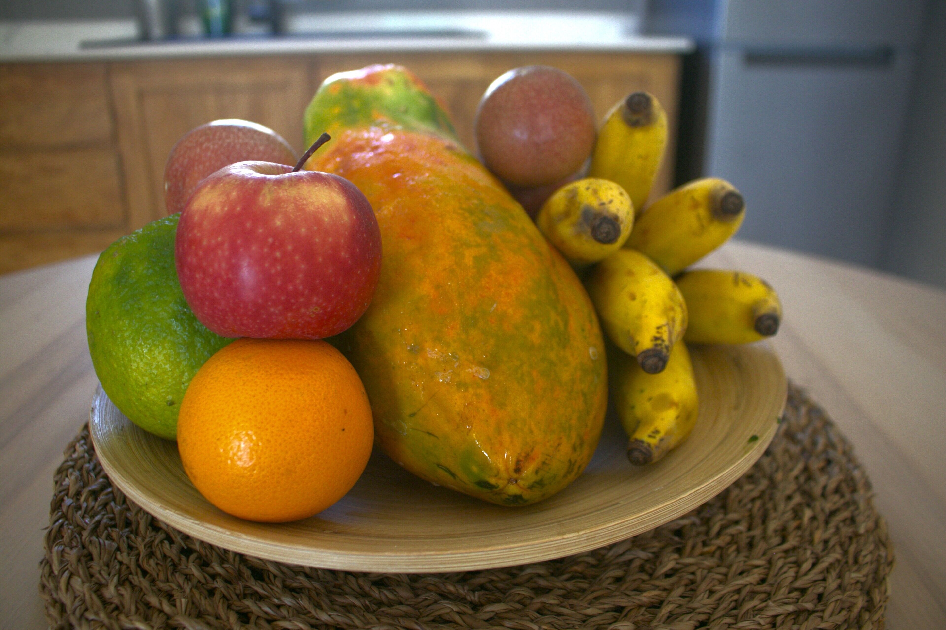 En tallerken med frugter, herunder æbler, appelsiner og bananer.