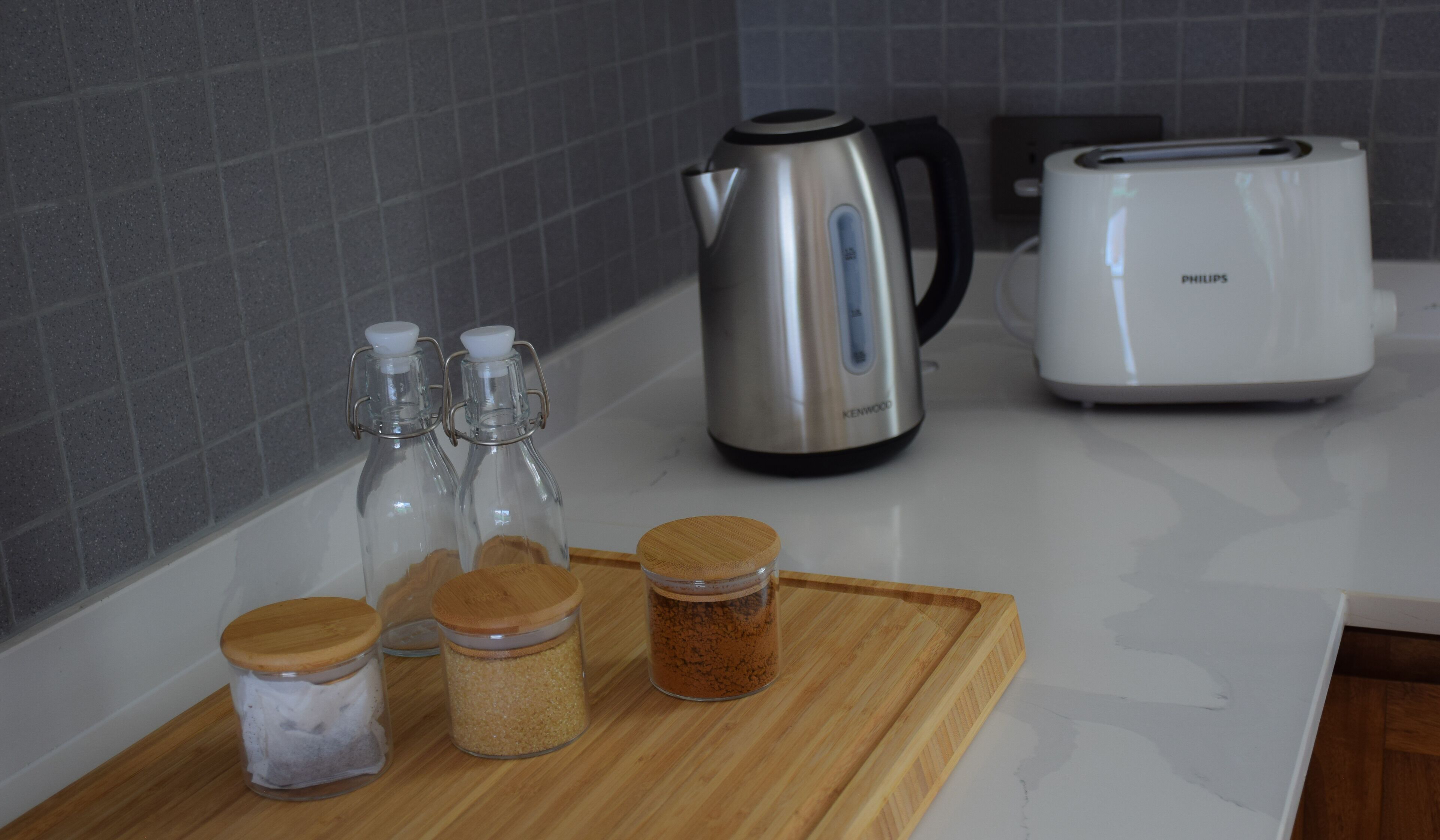 A kitchen counter with a kettle, toaster, and jars of spices.