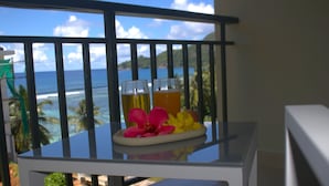 A balcony with a glass table holding two glasses of beer and tropical flowers. - Lagati Residence (Mahé Island)