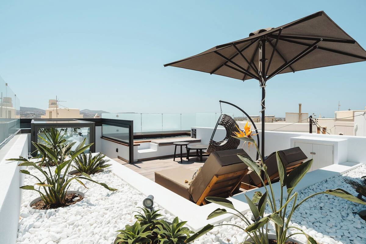 A rooftop terrace with a seating area, a grill, and a view of the cityscape.