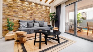 Ein modernes Wohnzimmer mit Steinwand, grauem Sofa, Holznachttischen und einer Glastür, die zu einem Außenbereich führt.