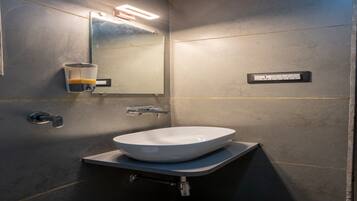Ein modernes Badezimmer mit einem großen Spiegel, einem Vessel-Waschbecken und einer wandmontierten Seifenspender.